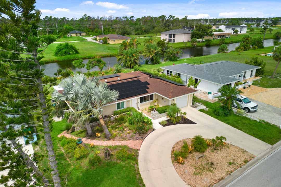 Aerial view of a residential neighborhood in Rotonda with single-story homes, landscaped yards, a winding road, and adjacent water bodies.
