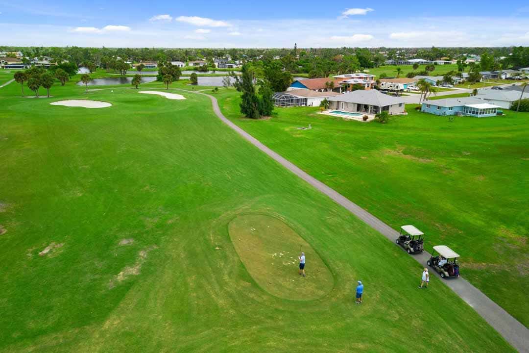 Aerial view of a golf course in Rotonda with players, golf carts, and surrounding residential area.