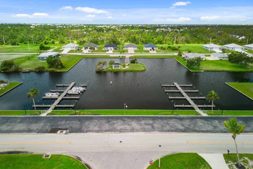 Aerial view of a residential area with houses surrounding a Rotonda-shaped man-made lake featuring several docks.