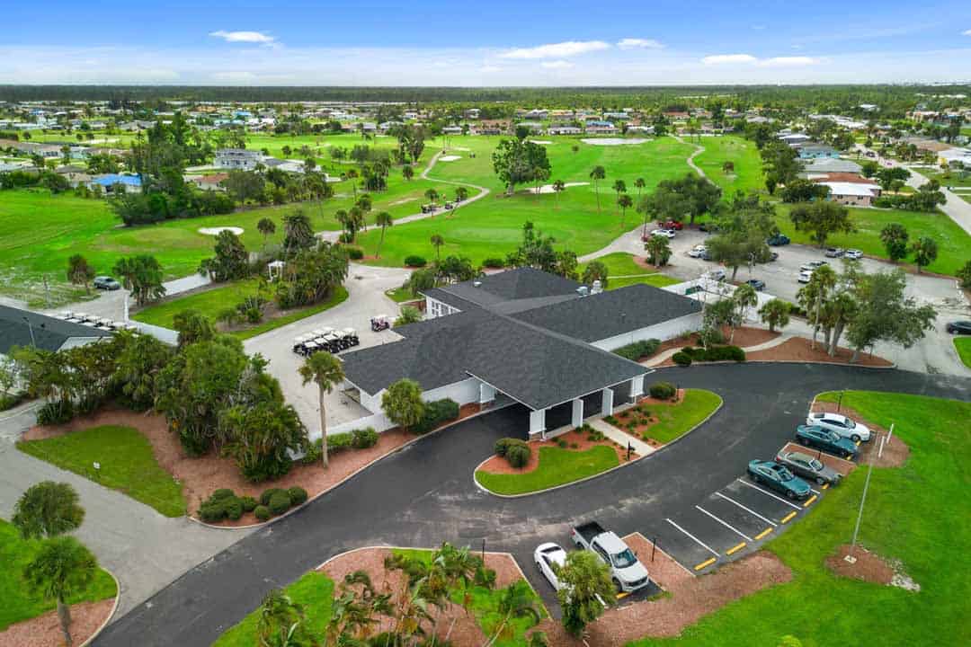 Aerial view of a large suburban golf club facility in Rotonda with a spacious parking lot, surrounded by well-maintained greens and residential areas.