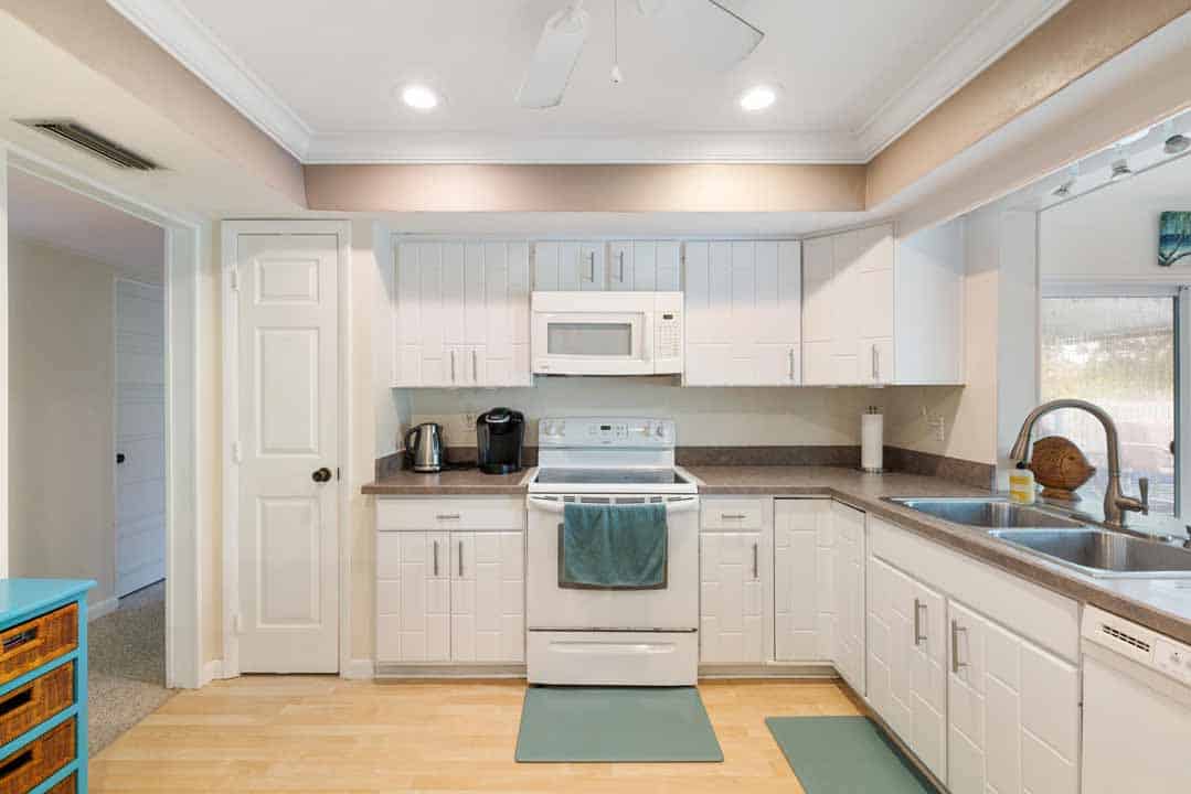 A modern kitchen interior featuring white cabinets, stainless steel appliances, and a granite countertop with a view through a rotonda window.
