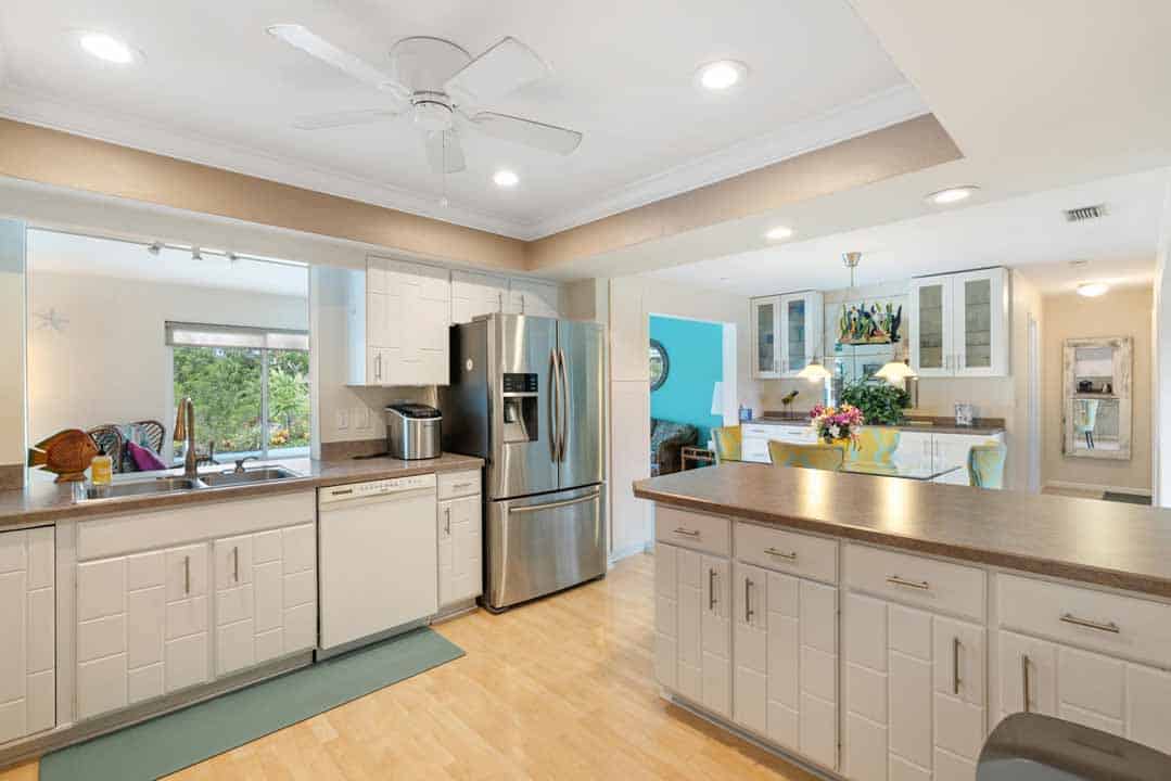 A modern kitchen with white cabinets, stainless steel appliances, and a wooden countertop, leading to an adjacent blue-walled living area in the Rotonda.
