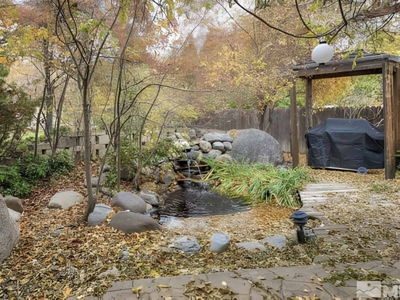 A serene garden scene with a small pond surrounded by rocks and autumn foliage. A covered outdoor grill is on the right under a wooden pergola.